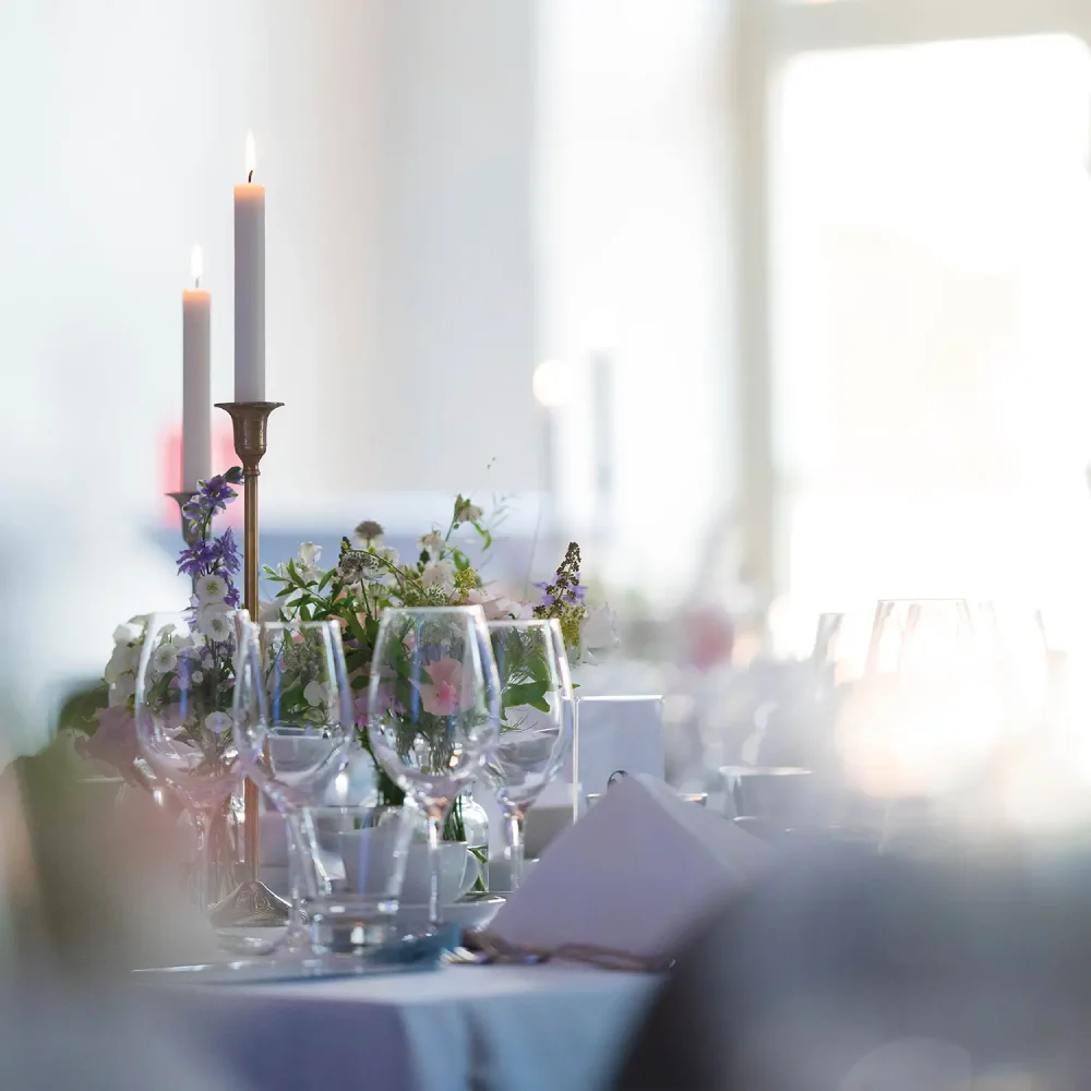 Elegant bordsdukning med levande ljus och blomsterdekor i ljus lokal.