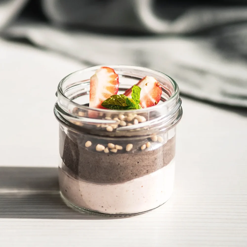 Dessert i glas med rödvinbärsmousse och oreocrème, toppad med färska jordgubbar, mynta och kolapärlor.