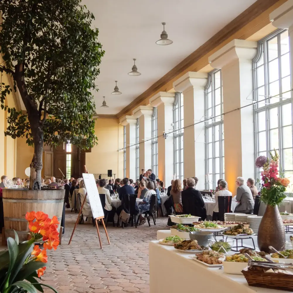 Festdukning med gäster och uppställd buffé i Botaniska trädgårdens orangeri i Uppsala.